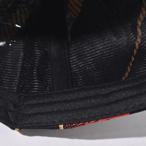 Close-up of baseball cap interior showing black mesh fabric and orange patterned brim
