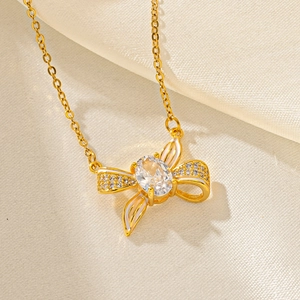 Golden butterfly bow necklace with clear zircon stones on soft beige satin fabric
