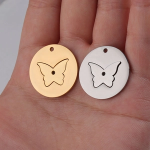 Mirror polished stainless steel butterfly charm pendants shown on palm for size scale