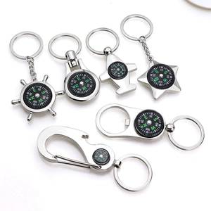 Polished silver metal compass keychains in various shapes like airplane and helm on white background