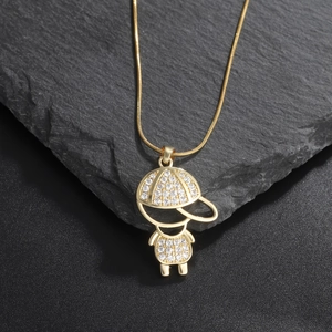 Close-up of a gold-plated boy pendant with sparkling zircons on a dark stone background