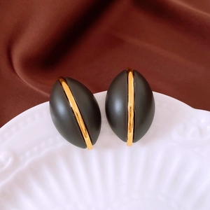 Detail of vintage French oval earrings in black resin with a gold vertical metal line