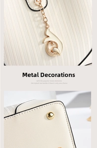 Detail of off-white leather handbag with gold swan charm and protective metal feet