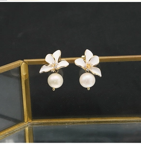 Detailed view of flower earrings with white enamel petals, zircon and teardrop pearl