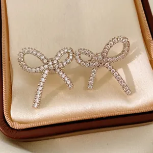 Elegant silver bow clip-on earrings with zircon stones displayed on a white satin gift box