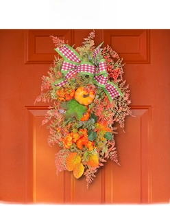 Detailed close-up of autumn door swag featuring pumpkins, maple leaves and plaid bow