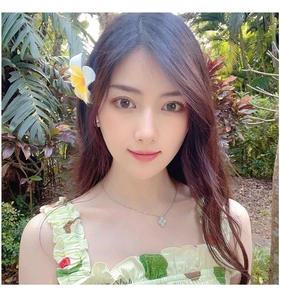 Silver clover necklace with white shell inlay worn by model in tropical garden setting