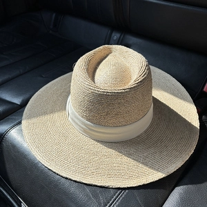 Detail of wide brim raffia sun hat showing the fine woven texture and satin ribbon