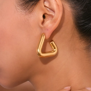 Macro view of geometric gold earrings with polished 18K gold plating on model's ear