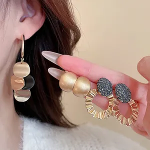 Three-piece gold earring set with drop disks, frosted spheres, and blue crystal hoops