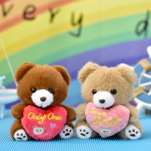 Detail view of two plush teddy bears holding red and pink embroidered hearts
