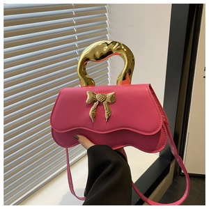Close-up of pink PU leather handbag with golden metal handle and a bow detail