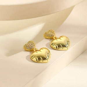 Macro view of gold heart earrings with micro-inlaid zircons and engraved striped details