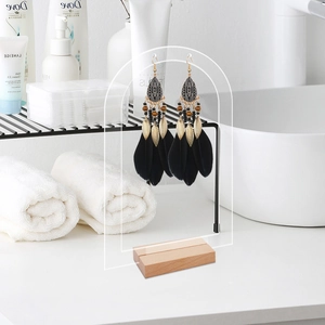 Détail du support à boucles d'oreilles en acrylique et bois avec boucles en plumes noires