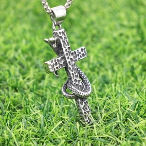 Gothic cross necklace with cobra snake pendant in vintage silver finish on green grass