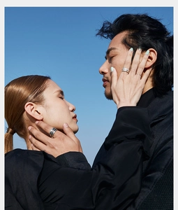 Detail of couple wearing vintage feather rings against a clear blue sky background