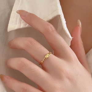 Detail of a minimalist gold heart ring with an openwork paperclip style chain band