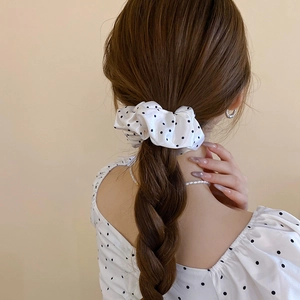 Close-up of a white satin scrunchie with black polka dots on a high ponytail