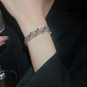 Macro view of three-layer silver bracelet featuring pink and white zircon crystals