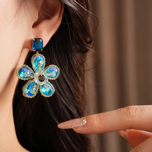 Gros plan de boucles d'oreilles vintage avec cristaux bleus sur un mannequin chic