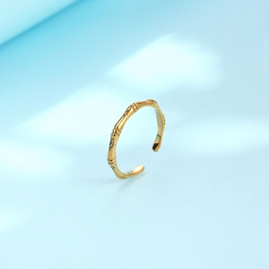 Adjustable golden bamboo-style stainless steel ring for women on a light blue background