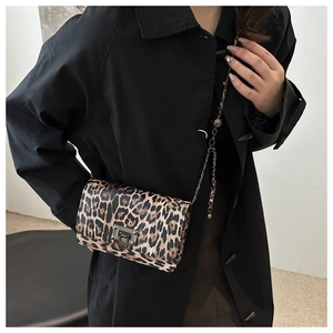 Detail of leopard print crossbody bag with metallic chain strap and stylish buckle lock