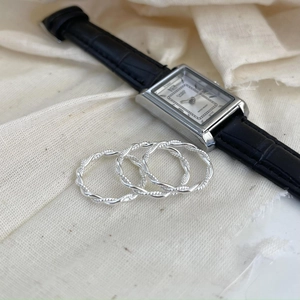Detailed close-up of three stacked 925 sterling silver braided twisted rings on linen fabric