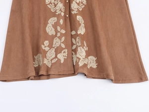 Detail of floral embroidery and buttons on brown faux suede dress hemline