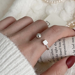 Detail of a 925 sterling silver open ring with round and square beads on a finger