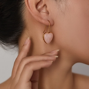 Close-up of pink resin heart dangle earrings on model with golden hooks for women