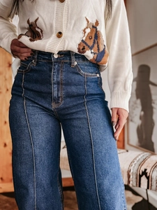 Macro-detail van de donkerblauwe jeans met hoge taille, verticale stiksels en retro-snit