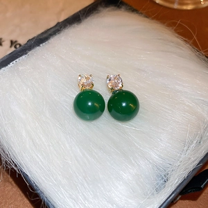 Vue macro de boucles d'oreilles dorées style français avec perles vertes et zircons