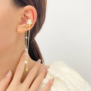 Detail of gold tassel ear cuff with small white flowers and elegant hanging pearls