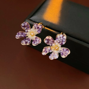 Detail of vintage flower C-shape earrings with purple crystals on black leather box