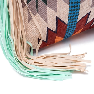Detail of bohemian woven bag featuring ethnic canvas patterns and soft mint tassels