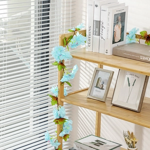 Light blue artificial flower vine garland draped over wooden shelf for home decoration