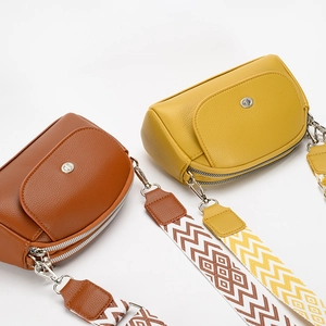 Minimalist leather shoulder bag with wide geometric patterned strap in brown and yellow