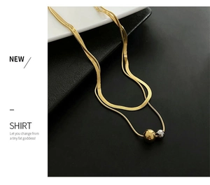 Detail view of double-layer snake chain necklace with gold and silver ball pendants