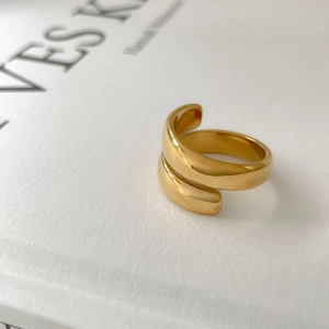 Close-up of golden multi-layer wrap ring on white book with soft lighting