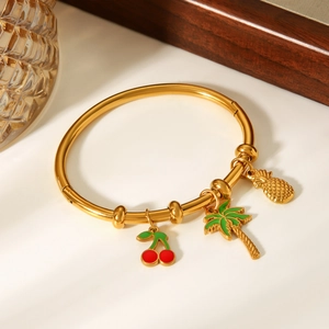 Dettaglio del bracciale in acciaio dorato 18k con ciondoli ciliegia, palma e ananas