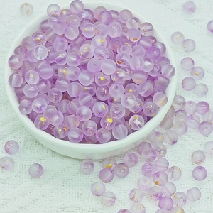 Close-up of 6mm frosted purple beads with gold foil accents in a white decorative bowl