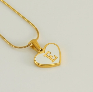 Detail shot of heart-shaped pendant with letter E engraving on a golden snake chain