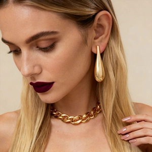 Minimalist golden teardrop earrings and chunky chain necklace set on professional model