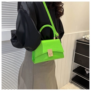 Detail of neon green stone pattern handbag with metallic clasp and woven top handle