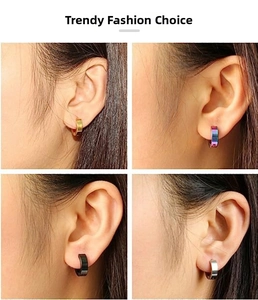 Detailed view of four colors of punk-style stainless steel huggie hoop earrings on ear
