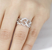 Close-up of heart-shaped infinity link ring in silver finish on hand with zircon stones