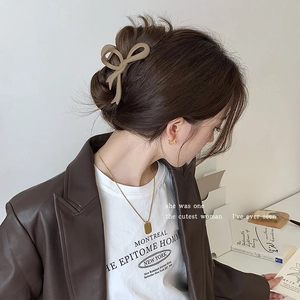 Detail view of a brown bow-shaped acrylic hair claw clip on a woman's bun hairstyle
