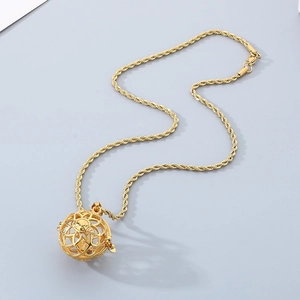 Close-up of golden hollow spherical sachet pendant on a twisted chain necklace