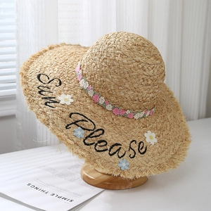 Close-up of hand-woven raffia sun hat with Sun Please embroidery and floral lace