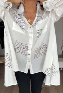 Detail eines weißen Oversize-Hemdes mit schwarzem Schreibschrift-Druck und Frontknöpfen